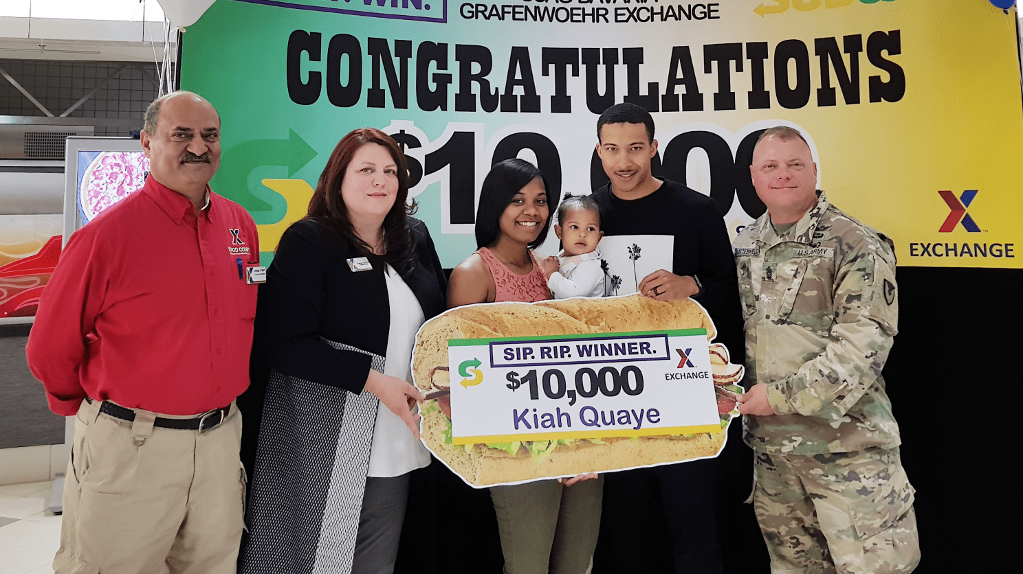Kiah Quaye $10,000 Winner (5) Exchange managers Aftab Khan and Carrie Cammel, along with USAG Bavaria CSM Micheal Sutterfield USAG Bavaria Command Sergeant Major present the $10,000 gift card to Kiah Quay and husband SPC Damion Quaye.