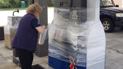 Marion Koenig Shift Manager preparing pumps for closure Shift Manager Marion Koenig wraps a gas pump in protective plastic at the Express before the store closes.
