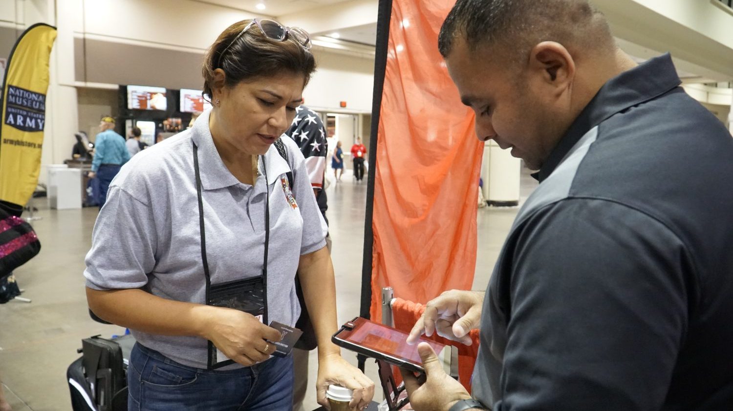 VOSB Image 3 From left, Army Veteran Francis Cordero Medina learns how to sign up for tax-free shopping at ShopMyExchange.com with help from Exchange Veteran Service Organization/Military Service Organization Outreach Manager Jose Hernandez at the VFW Convention this summer.