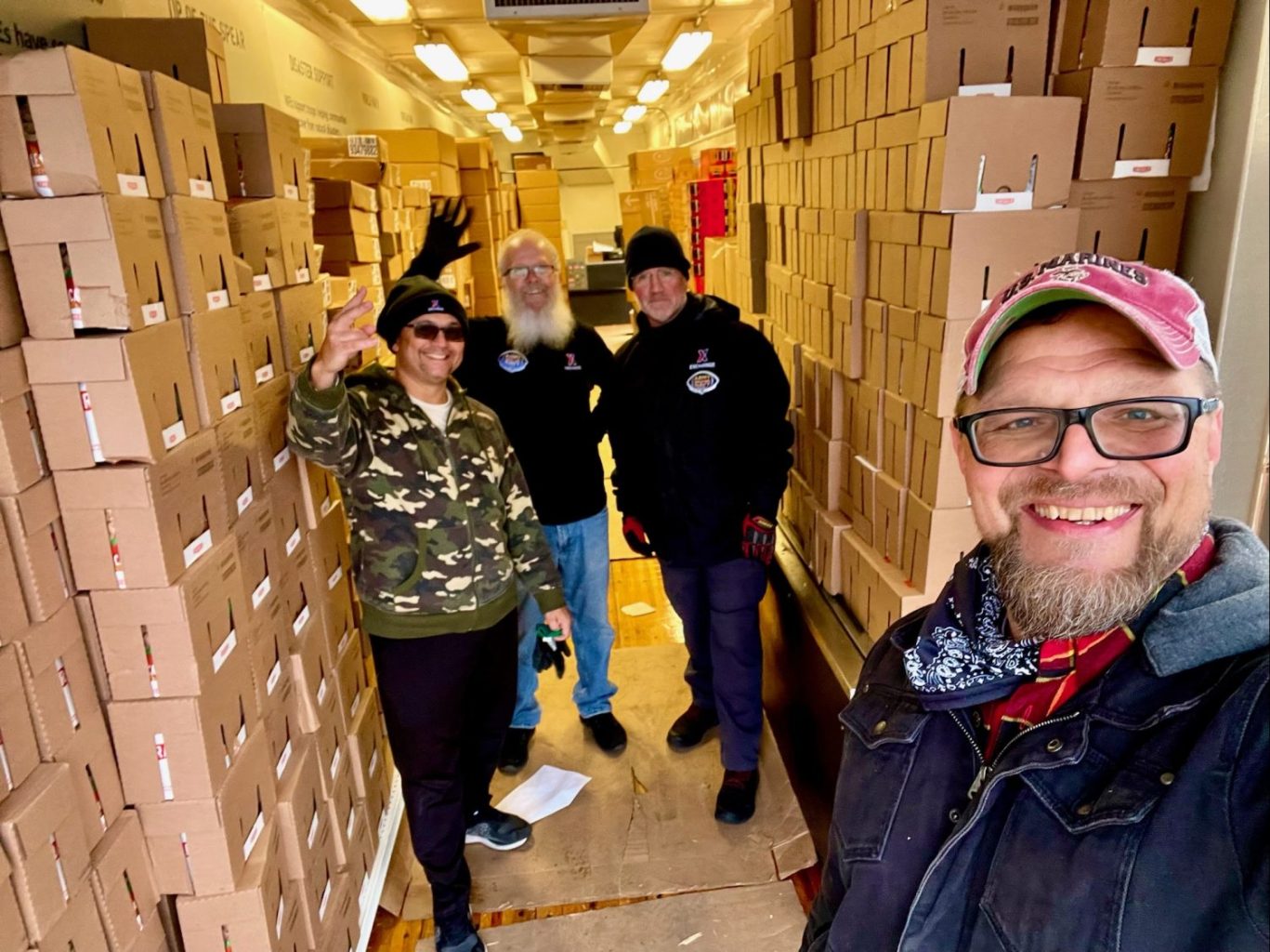 Arny-Navy)_20211209-210200-7a3eaf85 <strong>From left: Exchange truck drivers Eddie Hill and Bradley Wacks, Military and Veteran Outreach Manager Brian Schooley and Creative Director Johnny Olson get snacks ready fr the bonfire before the Army-Navy game.</strong>