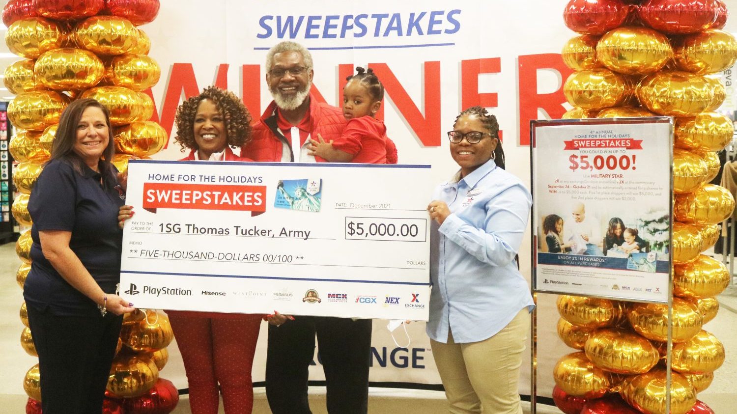 MILITARY STAR Home for the Holidays 2021 - Redstone Arsenal winner Redstone Arsenal Exchange General Manager Sheila Enderle (left) and Main Store Manager Chantel Scott (right) present retired Army 1st Sgt. Thomas Tucker with an oversized $5,000 check, the grand prize in the MILITARY STAR Home for the Holidays sweepstakes, Dec. 20 at the Redstone Exchange.