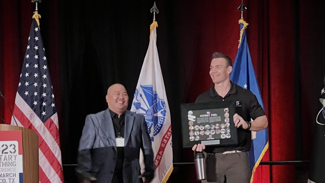 Gronk 4 <b>Exchange Divisional Merchandise Manager J.R. Chidester presents featured guest speaker Chris Gronkowski with an Exchange POG plaque at the 2023 Military Clothing conference.</.b>