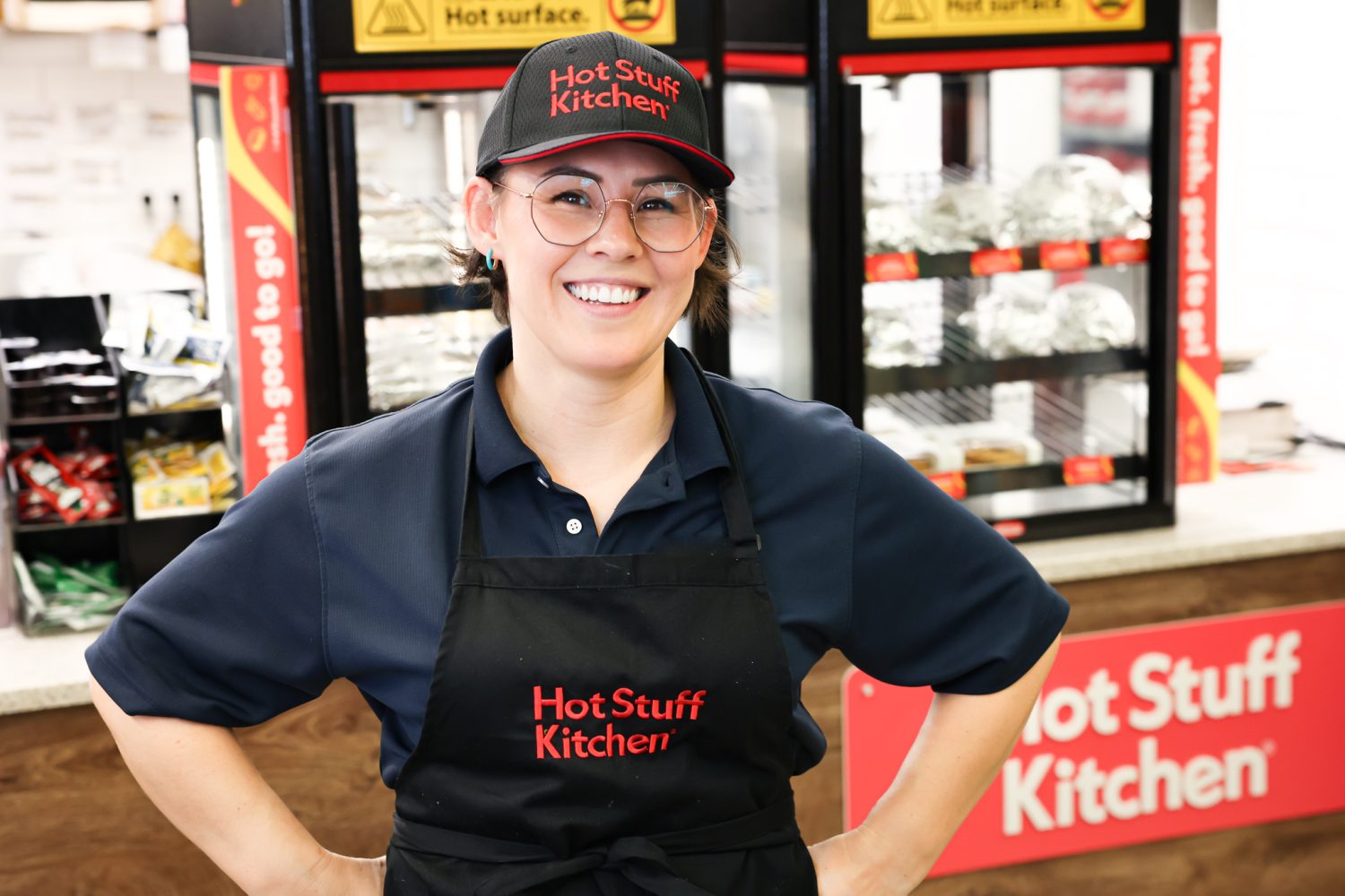 240711-A-WB953-0004 Pulaski Express store manager Ashlee Destajo in front of Hot Stuff Kitchen display.