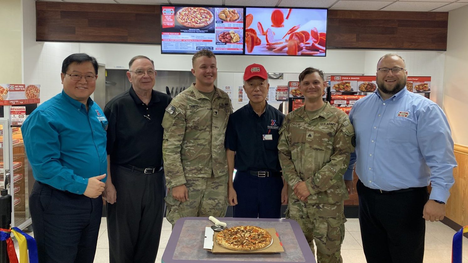 RR Range HBP GO 3 Exchange, restaurant and installation leaders with a Hunt Brothers Pizza ready for slicing.