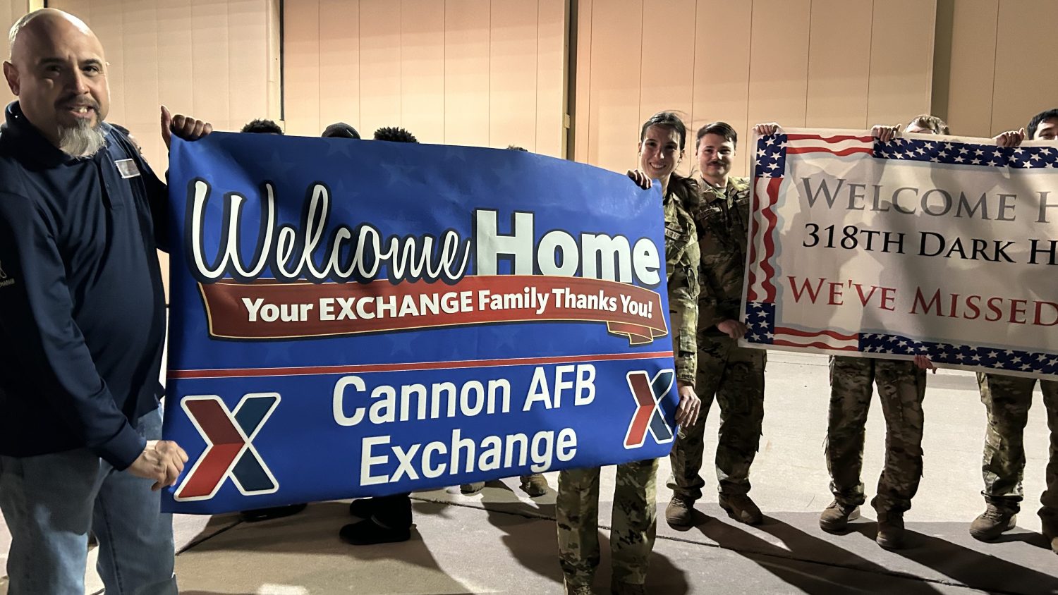 <b>Cannon AFB Exchange Administrative Assistant/Visual Merchandiser Eric Pena gets some help holding a welcome-home banner during a strong wind as the Cannon Community welcomed home 500 deployed troops home. 