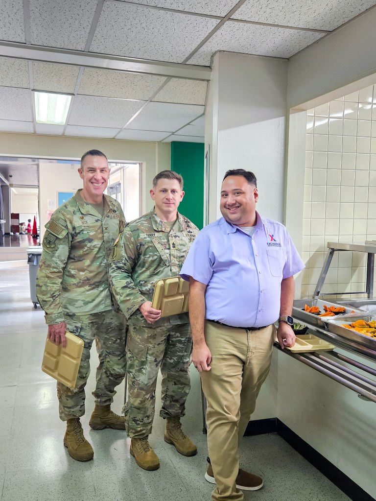Pacific Region Commander Air Force Col. Jason Beck, PAC Senior Enlisted Advisor Thomas Terry and Yokota GM Andrew Defelice get in line for the school meal program at Yokota West Elementary School.