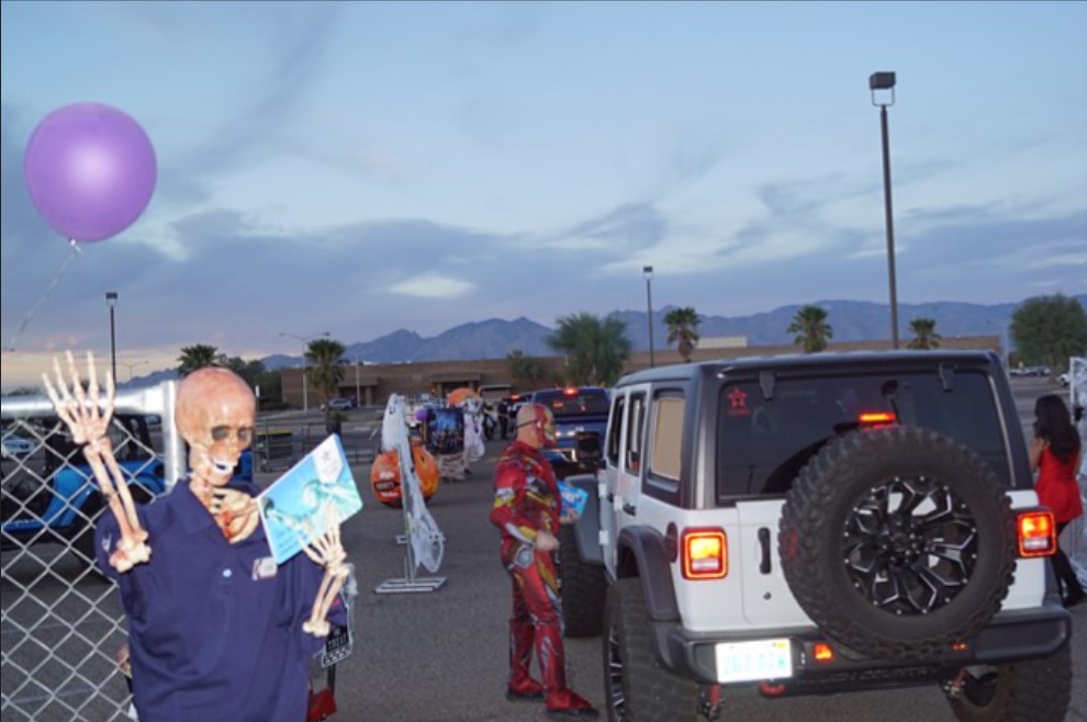 2020 photo of drive-thru trunk or treat event at Davis-Monthan AFB at dusk. Mountains in distance.