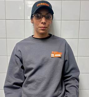 Photo of Traniece N. Davett, wearing shirt and cap with Dunkin' logo.