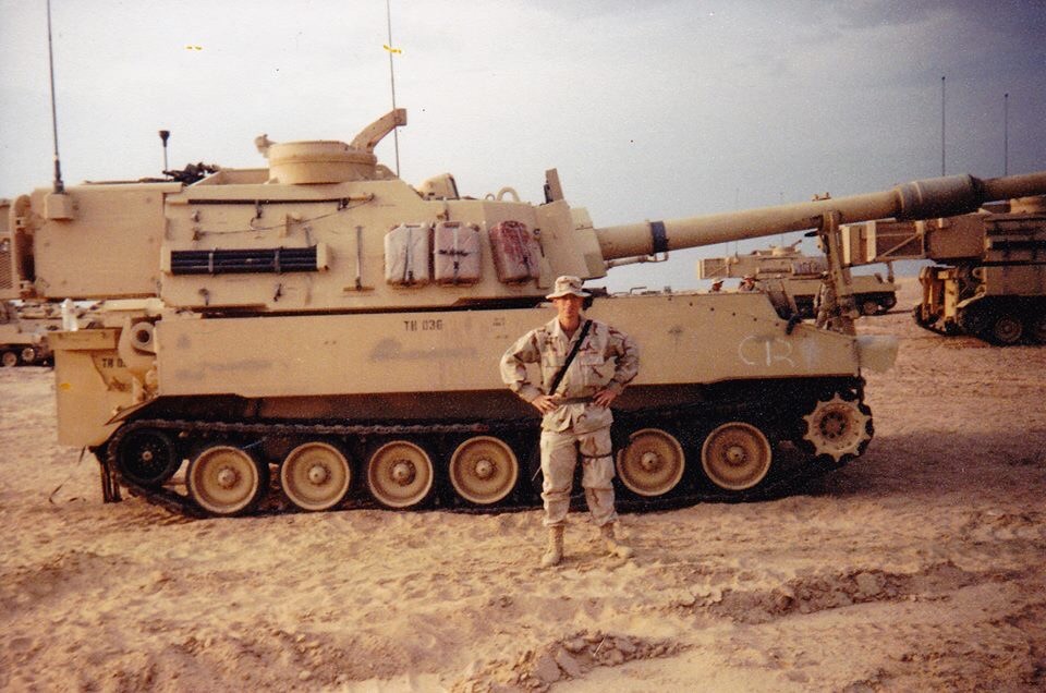 James Meyer standing in front of Army tank in Kuwait, 2001