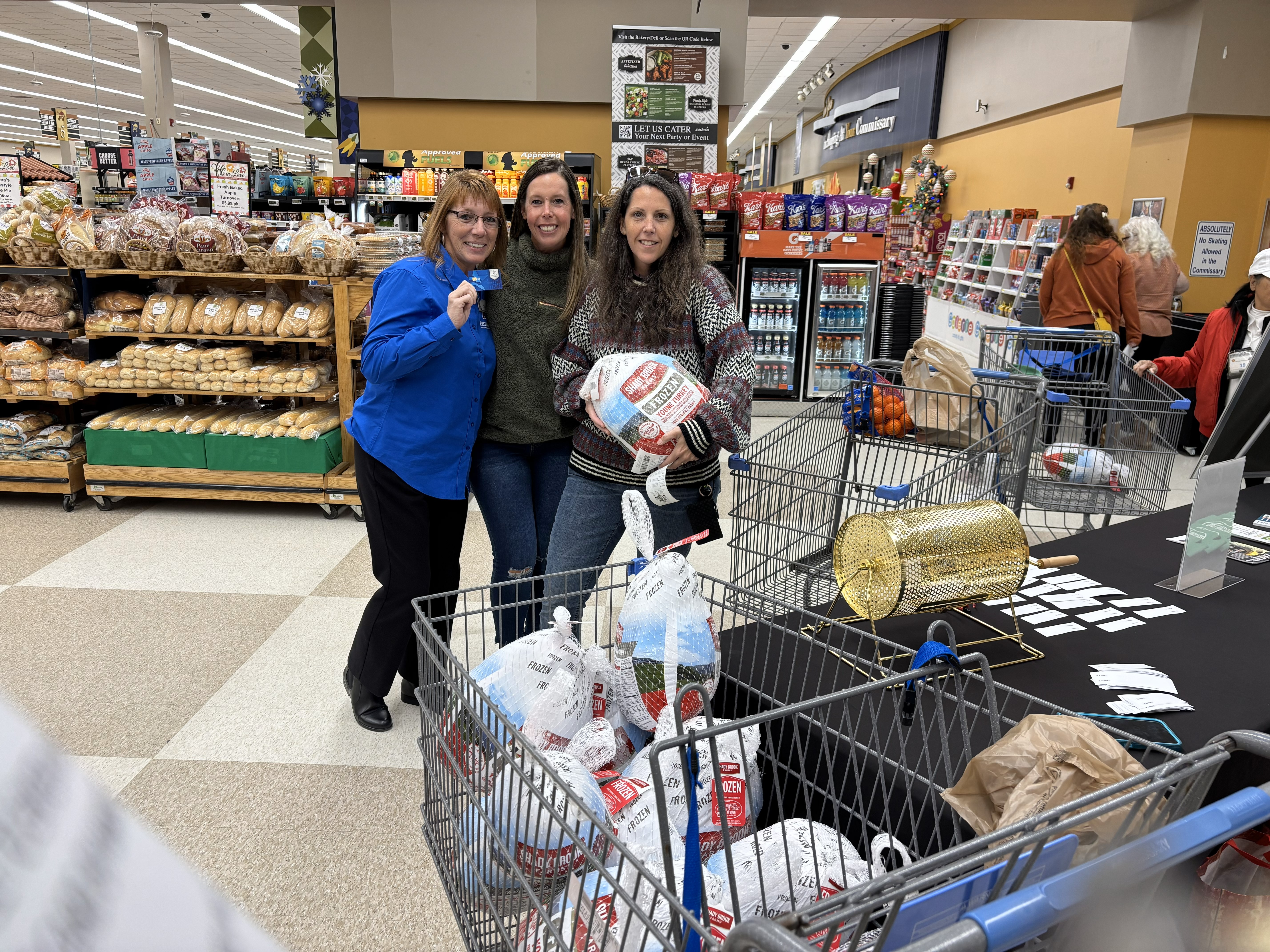 Exchange associates with a shopper and a shopping cart with frozen turkeys.