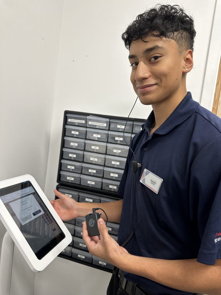 Associate using Theatro. He has a call button in his left hand and is wearing an earpiece.