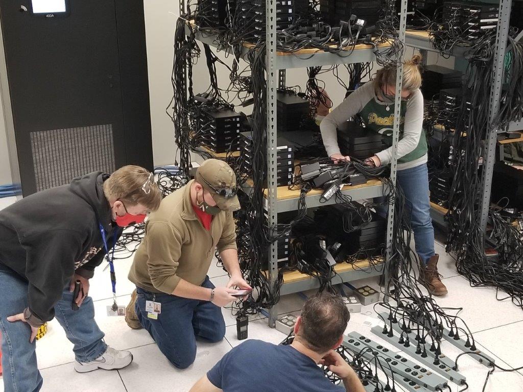 In a February 2021 photo, three men and a woman reconnect equipment at Exchange headquarters. They are wearing masks because of COVID restrictions at the time.