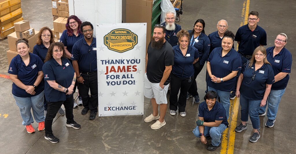 Exchange associates pose in a warehouse around a “Thank You James for All You Do!” National Truck Driver Appreciation sign.