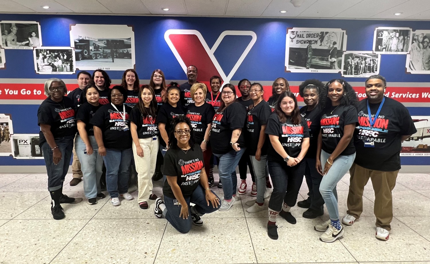 Group photo of Human Resources Support Center associates posing in headquarters hallway,