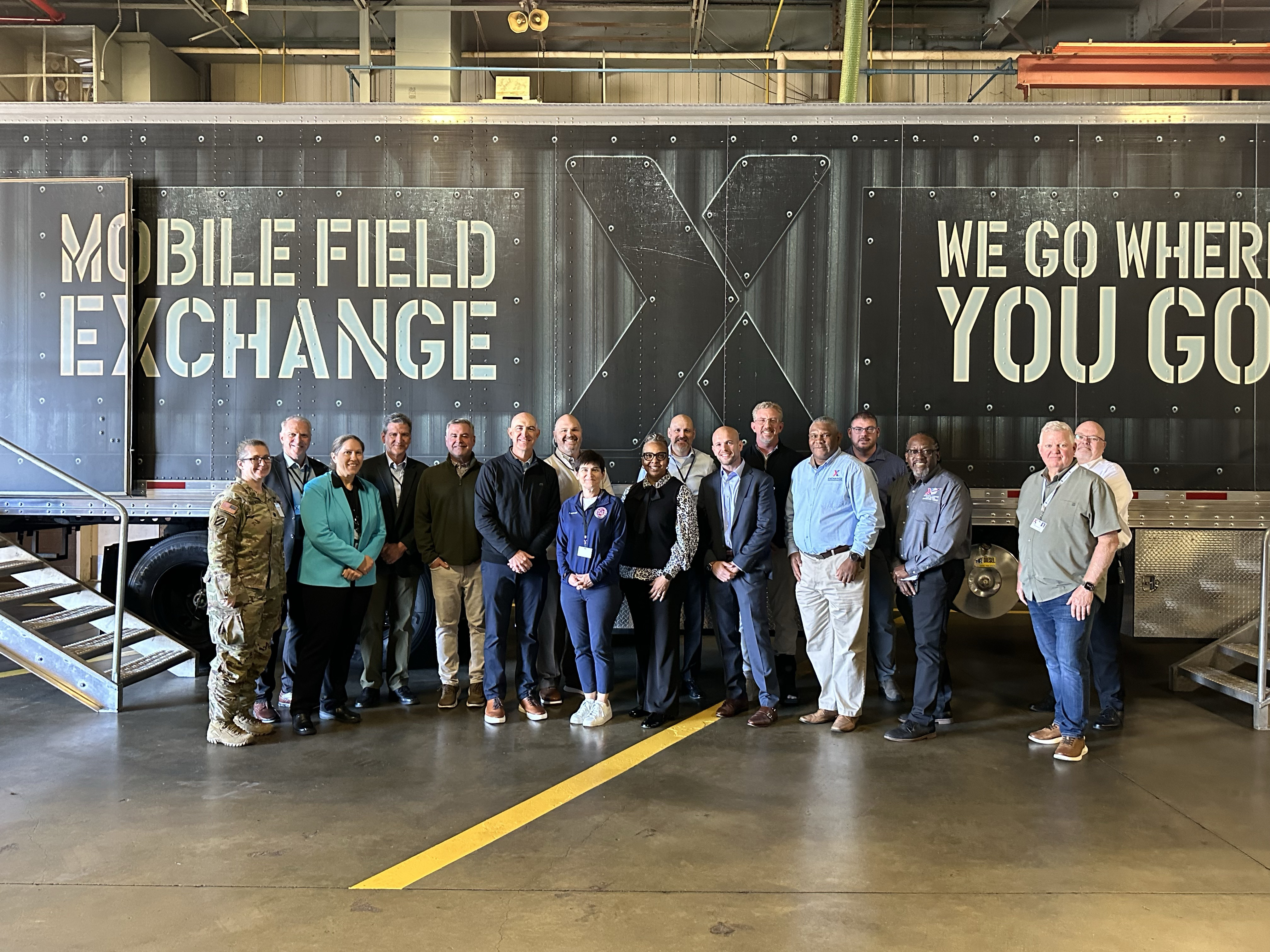 Group of people standing in front of a mobile field Exchange inside warehouse.