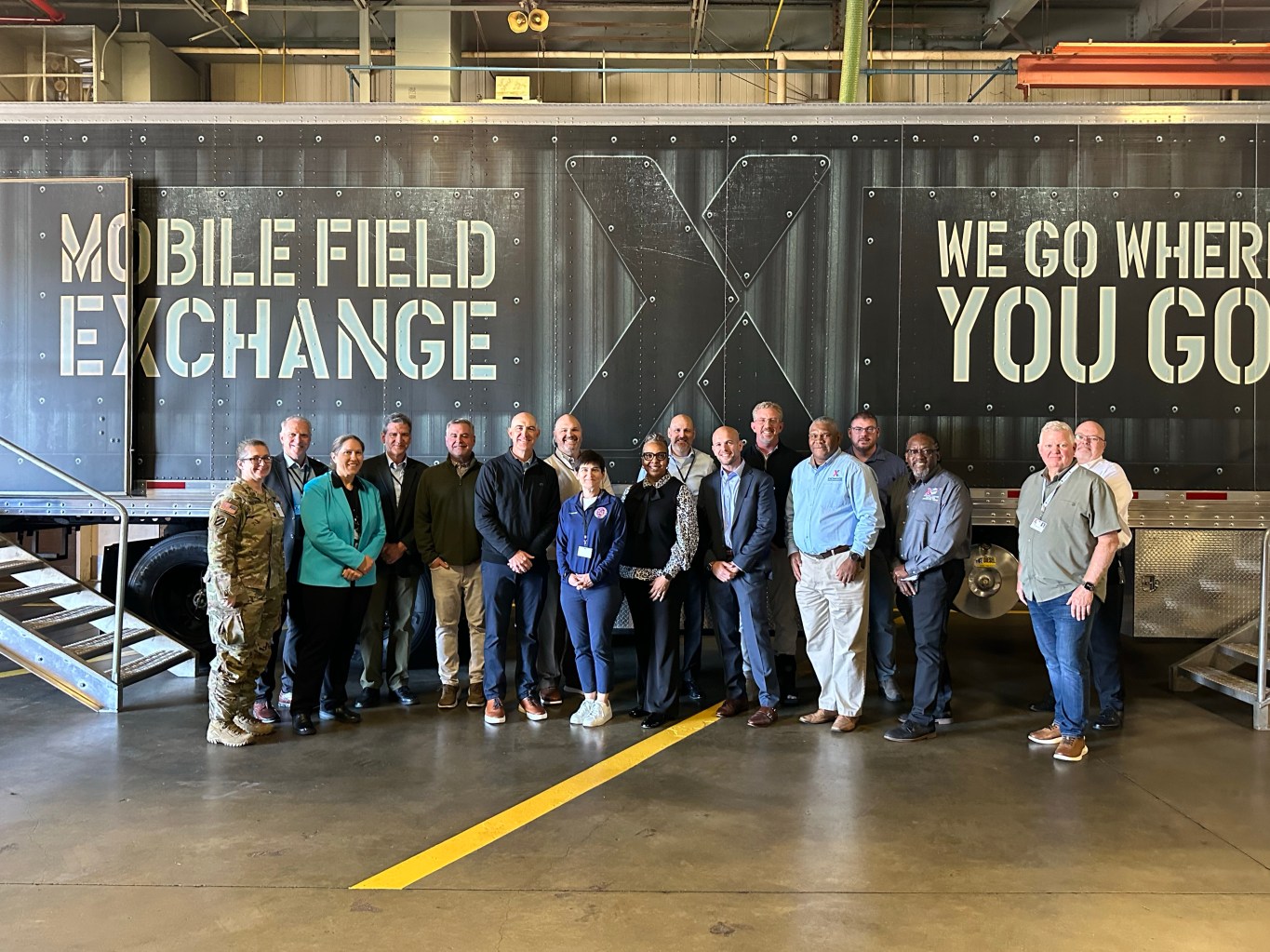 Group of people standing in front of a mobile field Exchange inside warehouse.